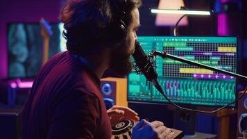 Music producer singing at home studio microphone to record songs, editing and adjusting volume levels in post production. Audio engineer conducts recordings of vocals, mixing console. Camera A. photo