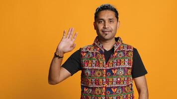 Portrait of jolly indian man with colorful garment smiling, looking pleased, isolated over studio background. Joyous person in traditional attire feeling carefree, camera A photo