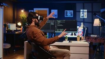 Remote software developer using VR goggles in personal office at home to do javascript programming. IT engineer wearing virtual reality headset in order to visualize lines of code, camera B photo