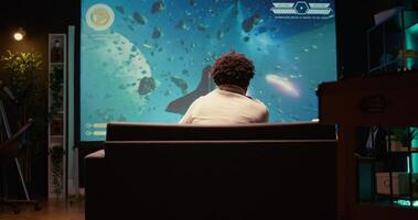 BIPOC man plays spaceship science fiction singleplayer game with overlay HUD showing health, fuel, ammo bars and minimap. Gamer enjoying high quality ray tracing graphics in videogame photo