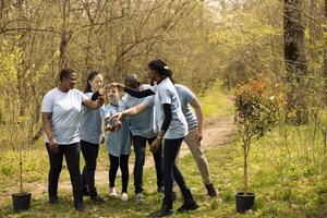 Thrilled group of helpers join hands in satisfaction, working together to fix natural areas affected by pollution. People assemble gladly to plant seeds, motivated by their ecological duty. photo