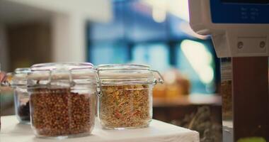 Grains and pasta as bulk products in glass jars at checkout in local organic shop, chemicals free pantry supplies and natural produce. Low carbon footprint eco friendly store. Handheld shot. Close up. photo