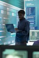 Governmental hacking specialist targeting sensitive information through high tech cyber attacks, digital espionage with a laptop and big screen. Hacker working on national security and data privacy. photo