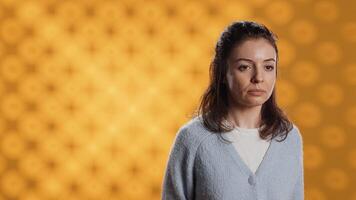 Portrait of relaxed woman posing, looking at camera, isolated over yellow studio background. Caucasian person dressed in casual attire standing, feeling confident, camera A photo