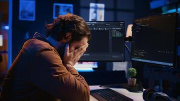 Annoyed software developer exasperated after failing to remove all bugs while coding on computer desktop. Teleworking IT specialist throwing keyboard, frustrated by script errors, camera B photo
