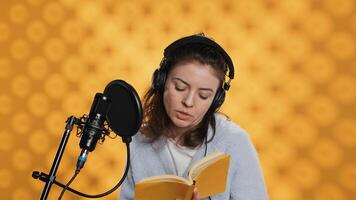 Lady browsing pages, doing voiceover reading of book to produce audiobook. Voice actor preparing to use storytelling skills to entertain audience while recording novel, studio background, camera A photo