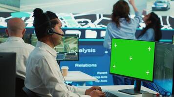 Indian operator monitors delivery trucks next to a mockup screen, uses surveillance footage on CCTV cameras around the city. Employee helps couriers to deliver orders, satellite navigation. Camera A. photo