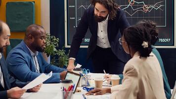 Startup team analyzing success metrics and key performance indicators to follow updates and establish changes, status update meeting. Coworkers measure progress towards strategic goals. Camera A. photo