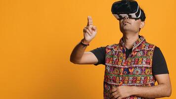 Indian man wearing virtual reality headset, doing swiping gestures. Technology enthusiast using high tech futuristic modern VR gadget, isolated over studio background, camera A photo