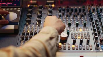 Sound designer working with sliders and switchers on control desk in professional music recording studio, editing and producing songs for a new album. Technician adjusting volume levels. Camera A. photo
