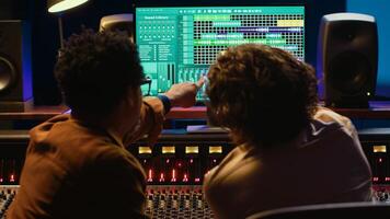 Diverse people processing and mixing sounds on audio console, adding sound effects and working on creating new tracks. Artist and technician producing a hit song, daw software. Camera A. photo