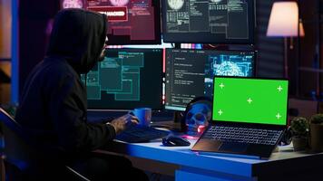 Green screen laptop used by hacker in underground hideout to write lines of code, developing virus that get past security systems. Chroma key device used by evil developer in hidden bunker, camera A photo