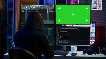 Dangerous man hacking using green screen PC, stealing credit card numbers and infiltrating banking systems. Hacker running code in apartment on mockup computer display, camera A photo