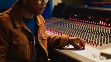 Professional artist singing a song on electro acoustic guitar in studio, recording his music on daw software mixing console in control room. Skilled musician producer composing tracks. Camera A. photo
