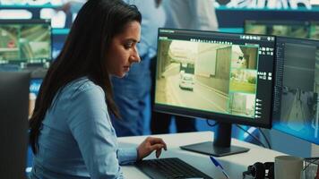 Indian woman operator locating delivery truck and offers gps coordinates of the shipment location. Control center employee consults satellite map and CCTV system for routes. Camera A. photo