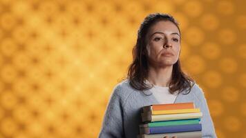 Portrait of upbeat woman holding pile of books, enjoying reading hobby for entertainment purposes. Radiant bookworm with stack of novels in arms enjoying leisure time, studio background, camera A photo