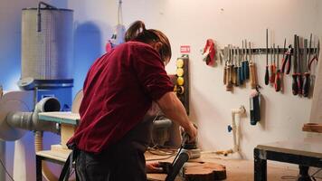 African american carpenter in joinery watching apprentice using orbital sander on lumber. Team in woodworking shop using angle grinder to create wooden decorations, refining wood objects, camera A photo