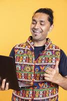 Cheerful employee doing thumbs up gesturing after receiving promotion at work, studio background. Joyful worker doing positive like hand gesture after reading good news on email on laptop photo