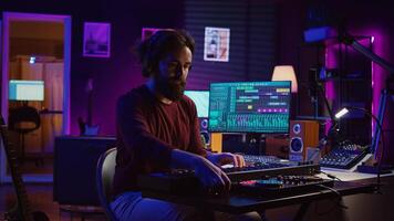 Young artist composing a song on electronic piano keyboard at home recording studio. Audio engineer playing MIDI controller, working on producing a soundtrack, soundboard tools. Camera B. photo