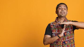 Portrait of assertive indian man asking for timeout, doing hand gestures, feeling fatigued. Firm person doing vehement pause sign gesturing, wishing for break, studio background, camera A photo