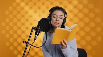 Internet star filming vlog at work, reading book to record audiobook, leaving studio after finishing. Narrator putting headphones down after being done producing digital recording of novel, camera B photo