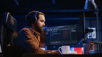Cheerful programmer listening music while doing web development during remote job shift in neon lit home office, finishing coding project. IT expert enjoying audio podcast, working on PC, camera B photo