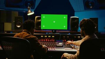 Diverse producers mixing and mastering tracks with mockup display on computer, recording before adding effects in post production. Artist and sound engineer twisting control desk knobs. Camera B. photo