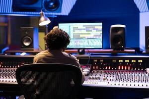 Sound engineer editing tracks with digital audio interface on computer, recording and processing tunes in control room. Audio expert producing and composing music with panel board. photo