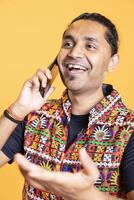 Happy man cracking jokes with best friend over telephone call using smartphone. Overjoyed person talking with mate in phone call using mobile phone, being entertained, studio background, close up shot photo