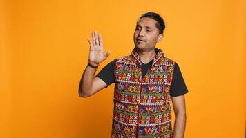 Indian man trying to stop chaotic fight using calming hand gesture to diffuse tensions, doing peaceful resolution. Reassuring person doing calm down sign gesturing, studio background, camera B photo