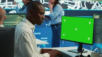 African american employee using greenscreen display and CCTV real time footage, communicating gps coordinates for order shipment and delivery. Control center operator uses surveillance. Camera A. photo