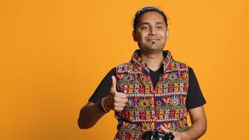 Gamer annoyed after losing online multiplayer videogame, being defeated by rival players. Indian man shocked and gutted after seeing game over message, holding controller, studio background, camera A photo