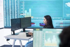 Enterprise analyst reviewing infographics numbers on a big screen at workstation, achieving strategic objectives in a competitive corporate environment. Employee improving efficiency. photo