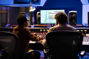 Team of artist and technician working on track recording in control room, mixing and processing songs with control panel board and technical equipment. Singer and sound designer producing tunes. photo