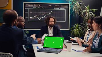 Business partners attending meeting next to greenscreen laptop, discussing the fate of the global enterprise and working on developing financial resources. Startup team address daily issues. Camera B. photo