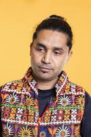 Pensive man reflecting, lost in daydreaming process, isolated over studio background. Distracted indian person in traditional clothing fantasizing, using imagination, studio backdrop photo