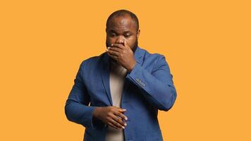 African american man covering mouth in disbelief, feeling upset by events, isolated over studio background. BIPOC person shaking head, left speechless by troubling news, camera A photo
