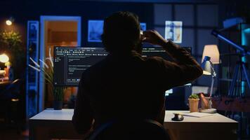Software engineer writes complex binary code scripts on computer, close up. Teleworking IT specialist in home office using programming to safeguard consumer data, handheld camera shot, camera B photo