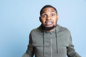 African american furious guy is getting into an argument and yelling in studio, serious aggressive person getting irritated. Frustrated man with anger issues being displeased, trauma. photo