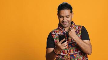 Happy man playing videogames on smartphone, celebrating after defeating foes, doing clenching hand gesture. Player swiping phone screen, thrilled about winning game, studio background, camera A photo