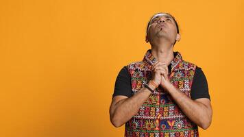 Indian man putting hands together in begging gesture, making wish, isolated over studio background. Faithful person asking for something, praying and hoping, believing in higher power, camera A photo