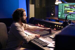 Mixing engineer working on blending individual tunes of a recording to create song for a new album, audio editing pc software in control room. Producer deals with technical aspects of sound. photo
