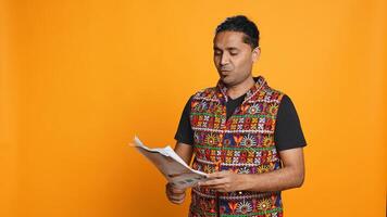 Indian man browsing though financial audit report files, throwing them in anger, feeling overworked, studio background. Stressed worker annoyed by paperwork, refusing to work anymore, camera B photo
