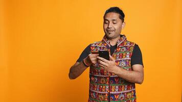 Man adding payment method on phone website, delighted to take advantage of promotions, studio background. Person thrilled to do internet shopping, typing credit card data on smartphone, camera B photo