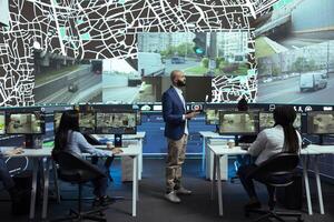 Middle eastern supervisor gives instructions to his team in control center, pointing at satellite navigation and CCTV surveillance to guide delivery couriers on their way to the destination. photo