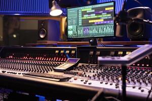 Control desk in professional music studio with motorized faders and knobs used in mixing and mastering tracks. Empty control room used in recording and producing songs, sound booth. photo