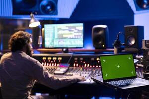 Audio producer working with isolated display on monitor in control room, recording and editing new music in professional studio. Skilled technician mixing and mastering tracks with console. photo