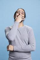 Middle eastern man feeling happy and amused with jokes in front of the camera, laughing and enjoying leisure time in studio. Young adult smiling and being joyful against blue background. photo