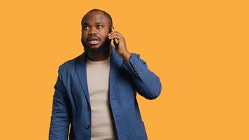 Joyous man with positive emotion, enjoying talking with friends phone call using smartphone, studio background. Happy african american person with smile on face during telephone call, camera A photo