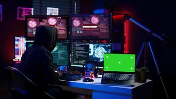 Green screen laptop used by hacker in underground hideout to write lines of code, developing virus that get past security systems. Chroma key device used by evil developer in hidden bunker, camera B photo